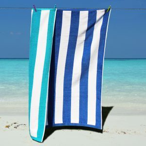 Blue and white striped luxury velour beach towel folded on a sun lounger