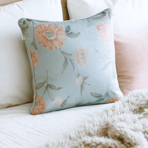 dahlia duck egg cushion on bed floral botanical design in duck egg blue with soft pink flowers